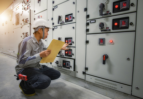Electrical maintenance technician working for checking and monitoring status high voltage circuit breaker switchgear electrical distribution substation in the factory