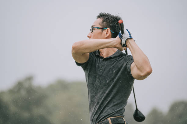 asian chinese male golfer playing golf in the rain in melaka alone wet tee off swing asian chinese male golfer playing golf in the rain in melaka alone golf concentration stock pictures, royalty-free photos & images