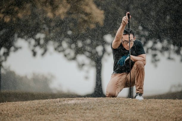 asiático chino golfista masculino alineado midiendo jugando al golf en la lluvia en melaka solo húmedo - golf power golf course challenge fotografías e imágenes de stock