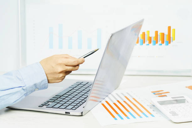 istock Finance. Female hand pointing at laptop screen financial graphs on desk 1267699642
