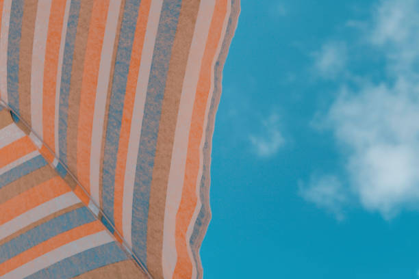 Beach umbrella viewed from below silhouetted against blue sky\nConceptual of vacation, tourism, relax