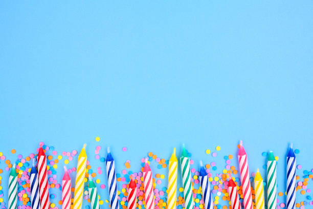 Birthday cake candles with candy sprinkles. Bottom border on a blue background. stock photo