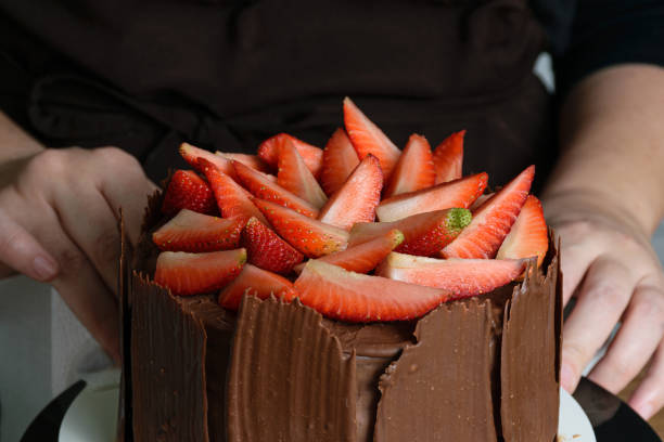 istock Chocolate cake covered with fresh strawberries, chocolate plates around it. 1267702205