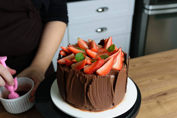 istock Chocolate cake covered with fresh strawberries, basil leaves and chocolate plates around it. Confectioner with blackberry jam. 1267702220
