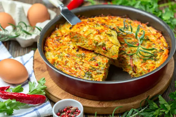 Vegetable Kugel of zucchini, carrots, potatoes, garlic and turmeric in a round baking dish. Dish of traditional Jewish cuisine.