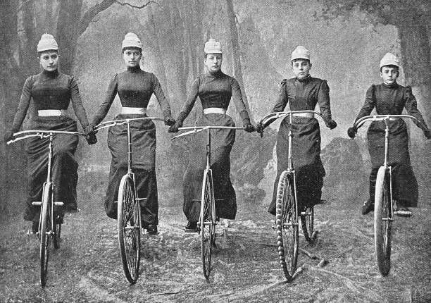Women Bicycle Club Graz, Austria, five women in a row on their bicycles, front view In comparison to the dangerous penny farthing bicycle with many serious injuries the newly developed bicycle with evenly low wheels was called safety bicycle. The first bicycle to be called a "safety" was designed by the English engineer Harry John Lawson (Henry Lawson) in 1876, although other bicycles which fit the description had been developed earlier, such as by Thomas Humber in 1868. It is the forerunner of all modern bicycles. With those lower wheels for the first time women in the 19th century were able to cycle, too, however in the beginning with those long clothes. Image from the 90ies of the 19th century. cycling photos stock pictures, royalty-free photos & images