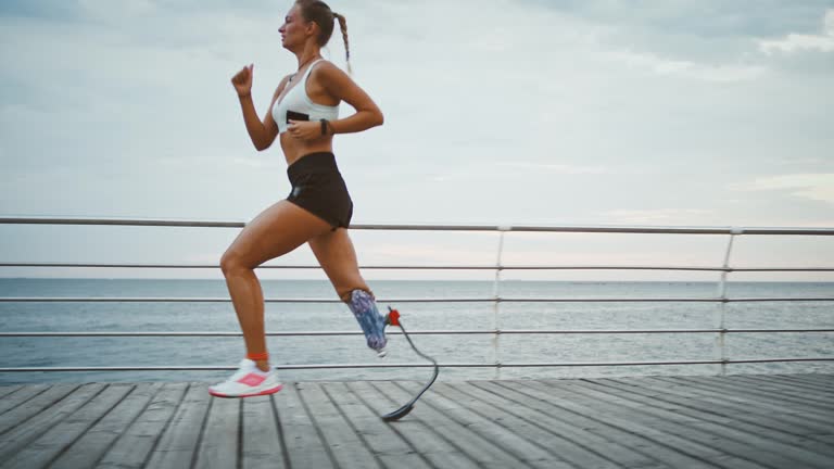 Young girl with prosthetic running on pier near sea