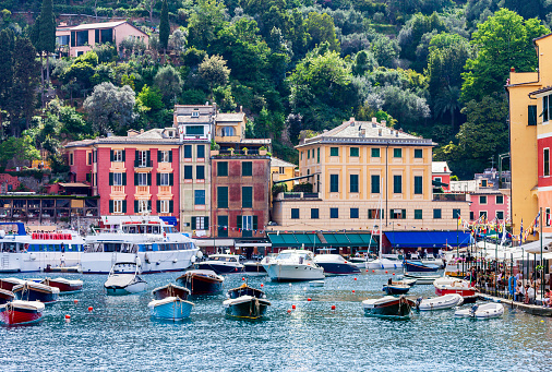 Boats, Businesses, Tourists and Beauty are what you see ias you enter the Portofino Italy Harbor. Tourists love to stroll the sidewalks by the bay in Portifino Italy shown here in late May.