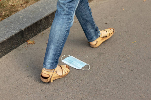 istock A woman steps on a medical mask lying on sidewalk. 1267712525