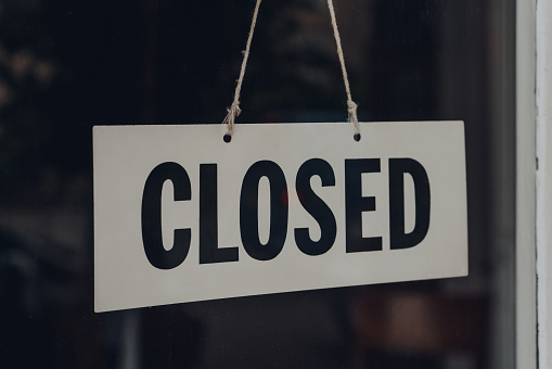 Black and white Closed sign on a glass front door of a restaurant.