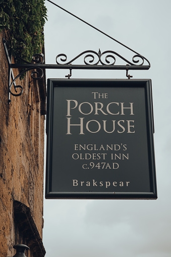 Stow-on-the-Wold, UK - July 10, 2020: Low angle view of a sign outside The Porch House, the oldest Inn and pub in England dating back to 947AD, located in Stow-on-the-Wold, UK.
