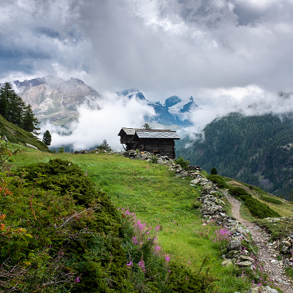 Swiss mountain scene with Monte Rosa peaks covered in clouds in the background.