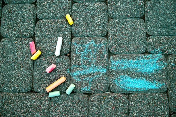 istock Blurred image Colorful pastel sidewalk chalk on dark asphalt background. children's crayons on the asphalt close up. The concept of development of children's creativity. selective focus. No focus 1267717762