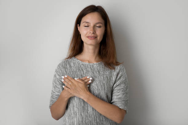 istock Grateful young woman keep hands at heart feeling thankful 1267719497