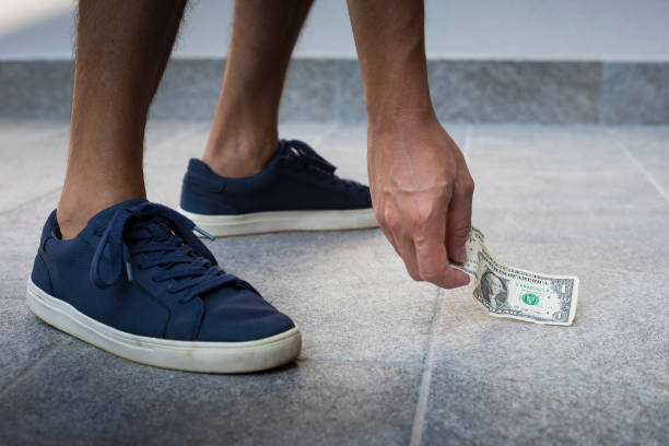 Finding and picking up money on the floor stock photo