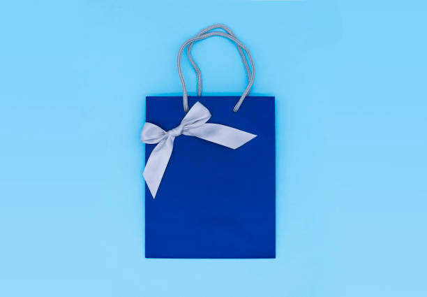istock A blue gift bag with a silver ribbon on blue background. Top view, copy space. Gift concept. New year, Woman's day. Valentine's day. Ready for birthday party. 1267719926