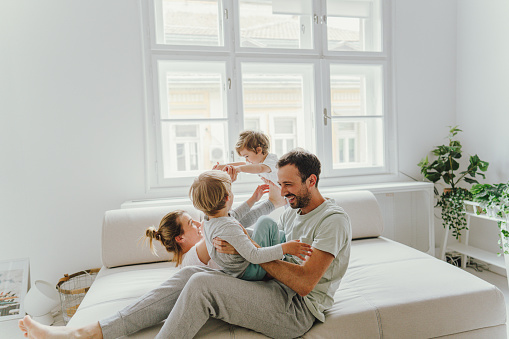 Photo of a young family being cheerful and playful after waking up; the morning routine of a young family.