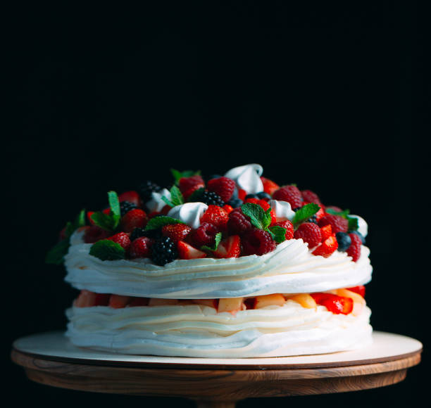 istock Fruit cake. Cake decorated with berries on a wooden stand on a black background. 1267723458