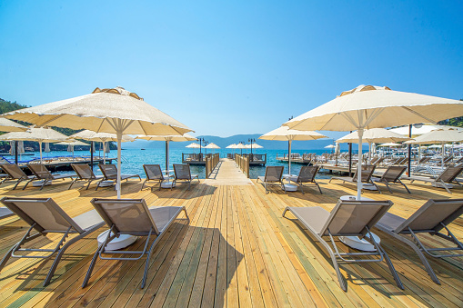 Sunbeds And Umbrellas With Wooden Pier On The Sea