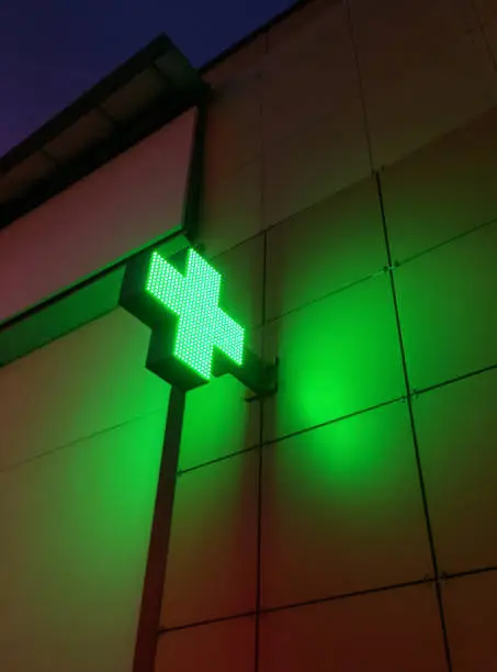 Photo of A green led pharmacy sign on the side of a building