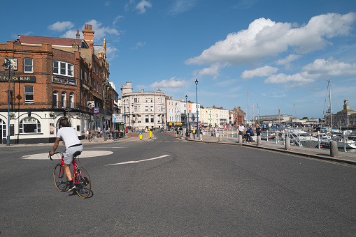 Ramsgate, UK - Aug 22nd 2020 A cyclist moves onto the main roundabout by Ramsgate Royal Harbour on a summer day.