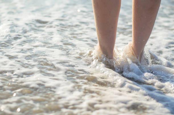 istock Women's legs are covered by the sea wave. 1267732153