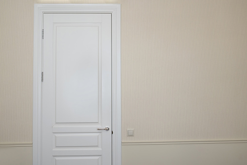 White door on a beige wall in an empty room. Details in the interior