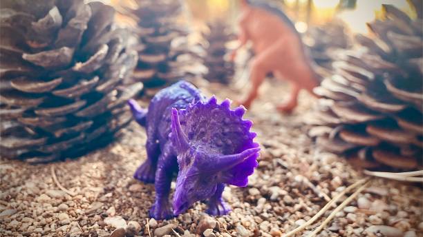 A small blue and orange plastic triceratops toy resting on a wooden surface, focusing on detail and color.