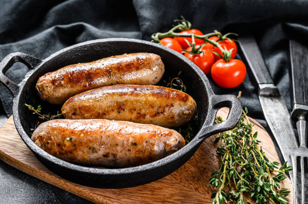 istock Pork sausages in a cast-iron pan. Black background. Top view 1267734502