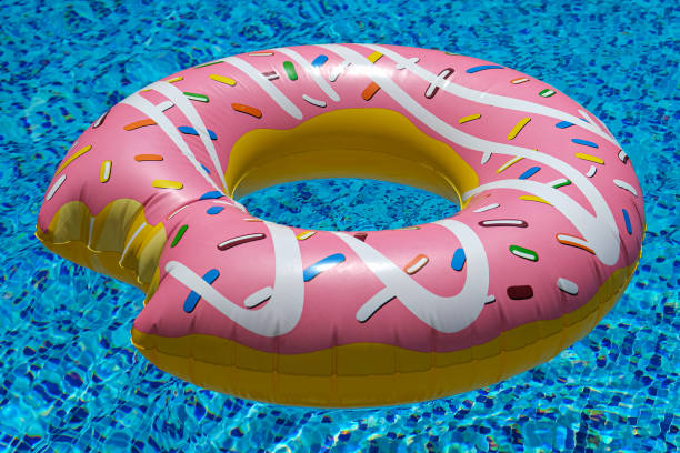 istock pink inflatable donut doughnut floating mattress in swimming pool. Beach pool accessories. Summer holiday concept 1267736423