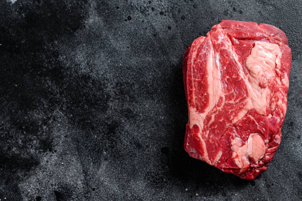 istock Fresh Raw meat Prime Black Angus Chuck roll steak.  Black background. Top view. Copy space 1267736531