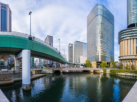 Elevated highways soaring over the tranquil waters of the Kyu-Yodo River reflecting the crowded skyscraper cityscape of downtown Osaka, Japan's vibrant second city.