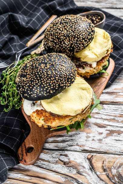 istock Burger with a black bun brioche, scrambled eggs, beef Patty and arugula. White background. Top view. 1267738277