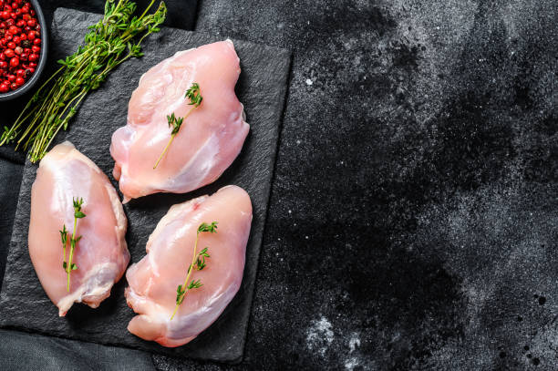 istock Chicken thigh fillet without skin. Black background. Top view. Copy space 1267738316