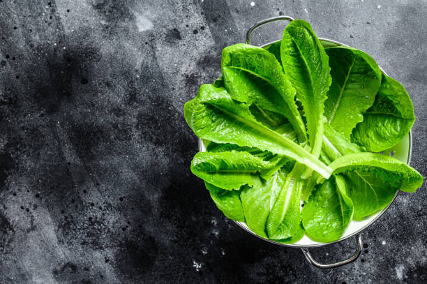 istock Romaine lettuce salad in a colander. Black background. Top view. Copy space 1267739043