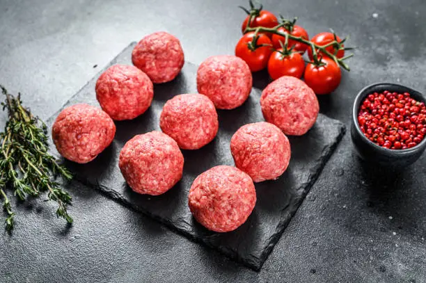 Photo of Raw meatballs, minced pork meat. Black background. Top view