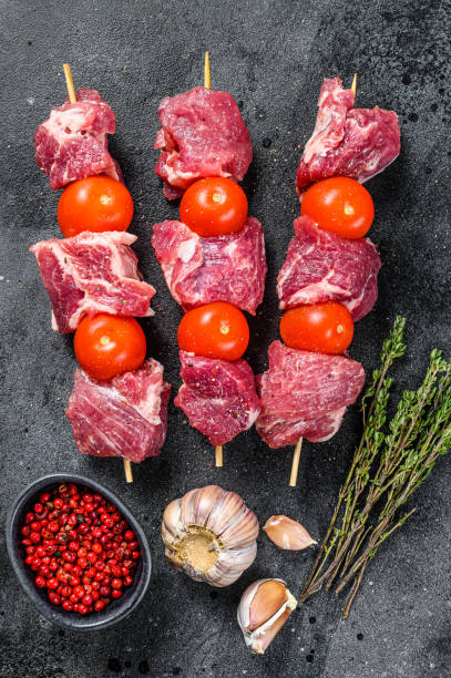 istock Raw beef meat kebab. BBQ with tomato and spices.  Black background. Top view 1267739917