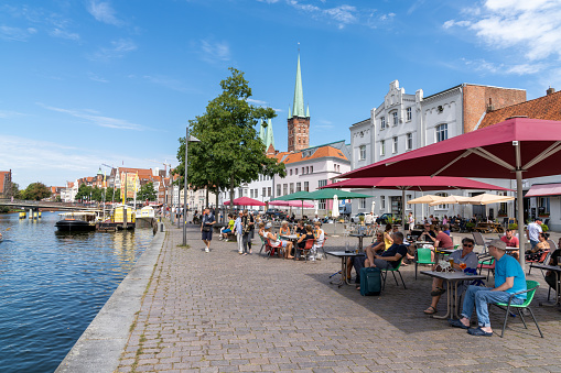 Lüebeck, S-H / Germany - 9 August 2020: people enjoying a summer day by the riverside in historic old town Lubeck