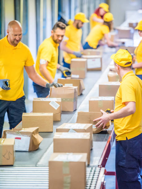 istock Postal workers working with packages at a conveyor belt 1267748011