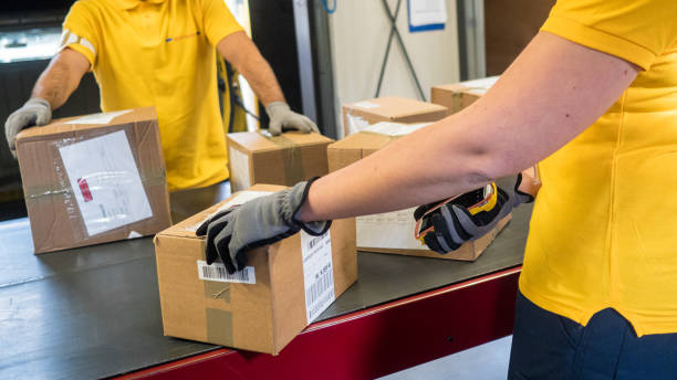 istock Postal workers handling boxes at a conveyor belt 1267748025