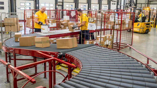 istock Postal office workers handling boxes at the end of a conveyor belt 1267748038