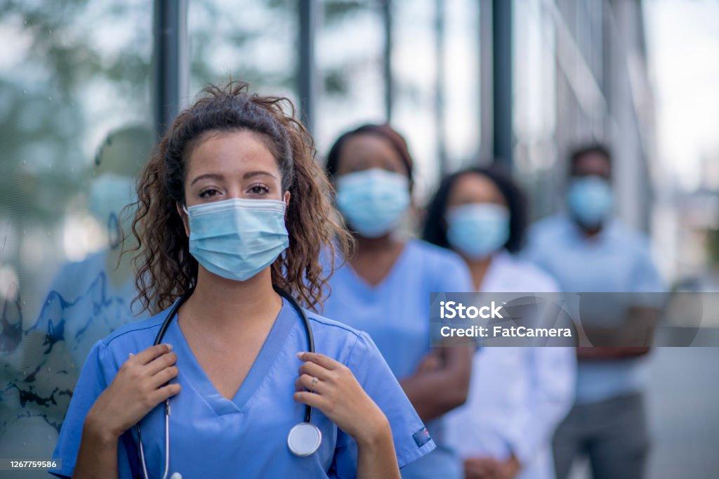 Group of doctors outside Diverse group of medical professionals outside the hospital wearing protective face masks. Nurse Stock Photo