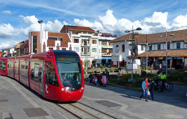 Red city tramway in historical center of city Cuenca, Ecuador Cuenca, Ecuador - May 27, 2020: Red city tramway (tram) crosses Plaza Civica, trading square in front of agriculture market 9 de Octubre in historical center of city Cuenca, UNESCO world heritage site cuenca ecuador stock pictures, royalty-free photos & images