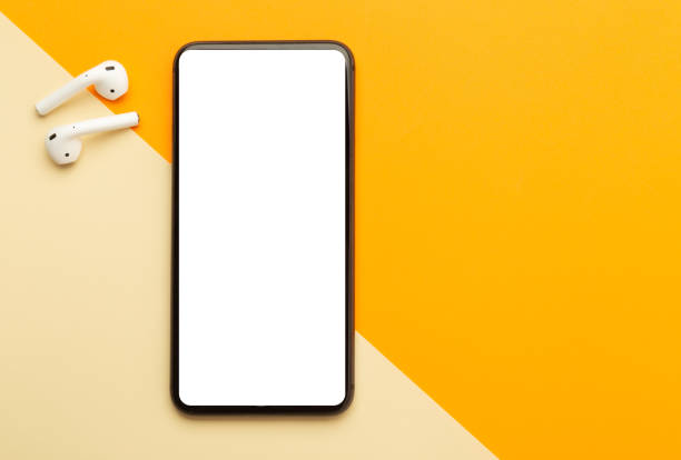 istock Flat lay, top view of orange office table desk with smartphone blank screen mockup with clipping path and wireless earphones. Modern working space 1267770755