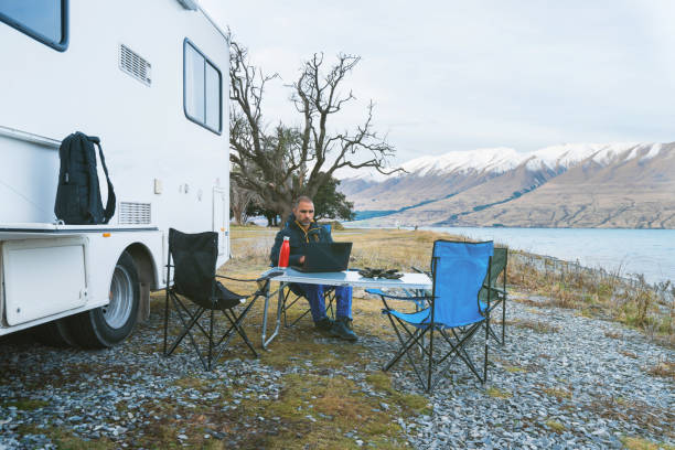 un homme travaillant sur l’ordinateur portable d’un endroit éloigné. - motor home park camping luxury photos et images de collection