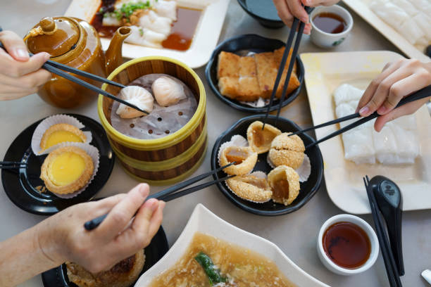 istock Flat lay Chinese dim sum time, various traditional dim sum freshly served on table and human hands picking up with chopsticks 1267807507
