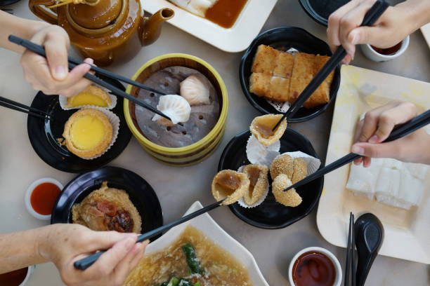 istock Flat lay Chinese dim sum time, various traditional dim sum freshly served on table and human hands picking up with chopsticks 1267807514