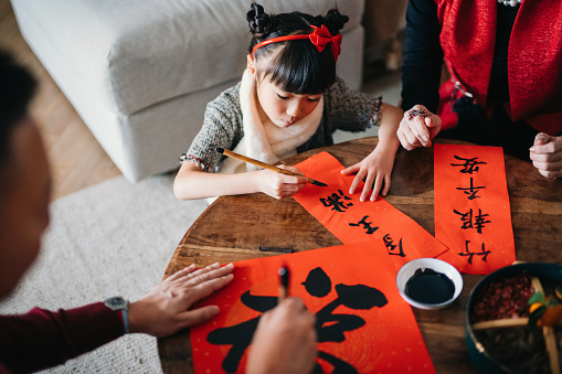 Abuelos practicando la caligrafía china para el Año Nuevo Chino Fai Chun (Mensajes Auspiciosos) y enseñando a su nieta escribiéndola en copas en casa photo