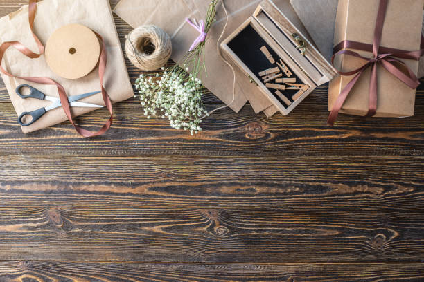 istock Craft paper and tools for creating and decorating gift packaging. There is cardboard, brown ribbons and rope on a wooden table. Concept of a creative approach to creating gift packaging with handmade. 1267808313