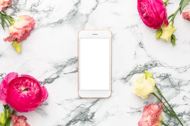 Pink and white flower bouquet with mobile phone on marble background with copyspace top view